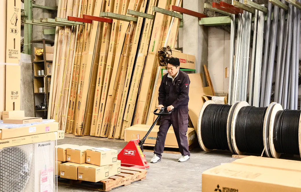 倉庫でパレット台車を使い荷物を搬送する社員