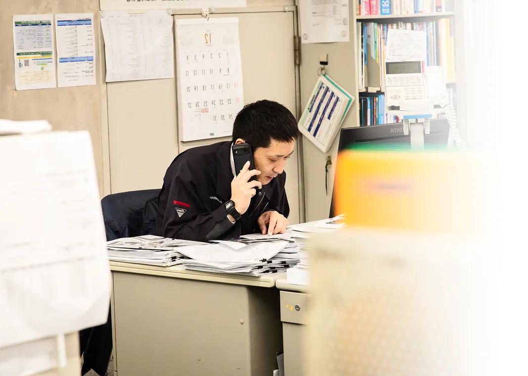 デスクで電話対応を行いながら業務を進める社員