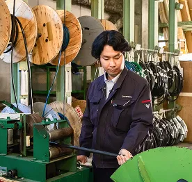 倉庫で電線加工機を操作する社員