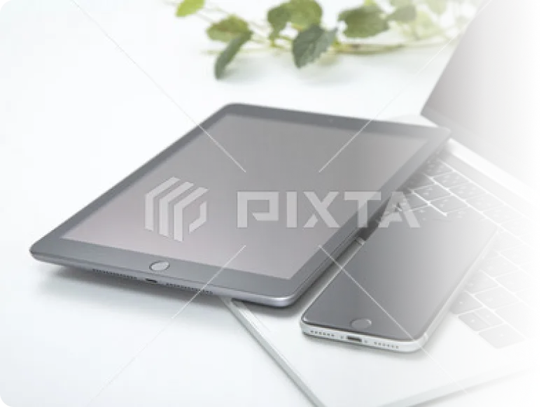 ノートパソコンとタブレット、スマートフォンを使ったIT機器イメージ